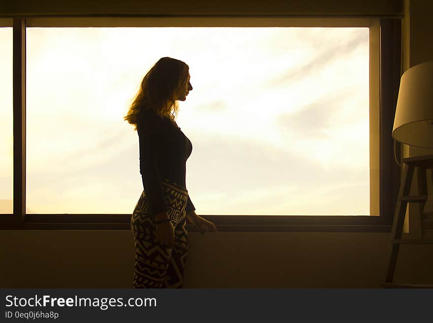 Woman in Black Long Sleeve Shirt and Tribal Leggings Standing by the Window during Daytime