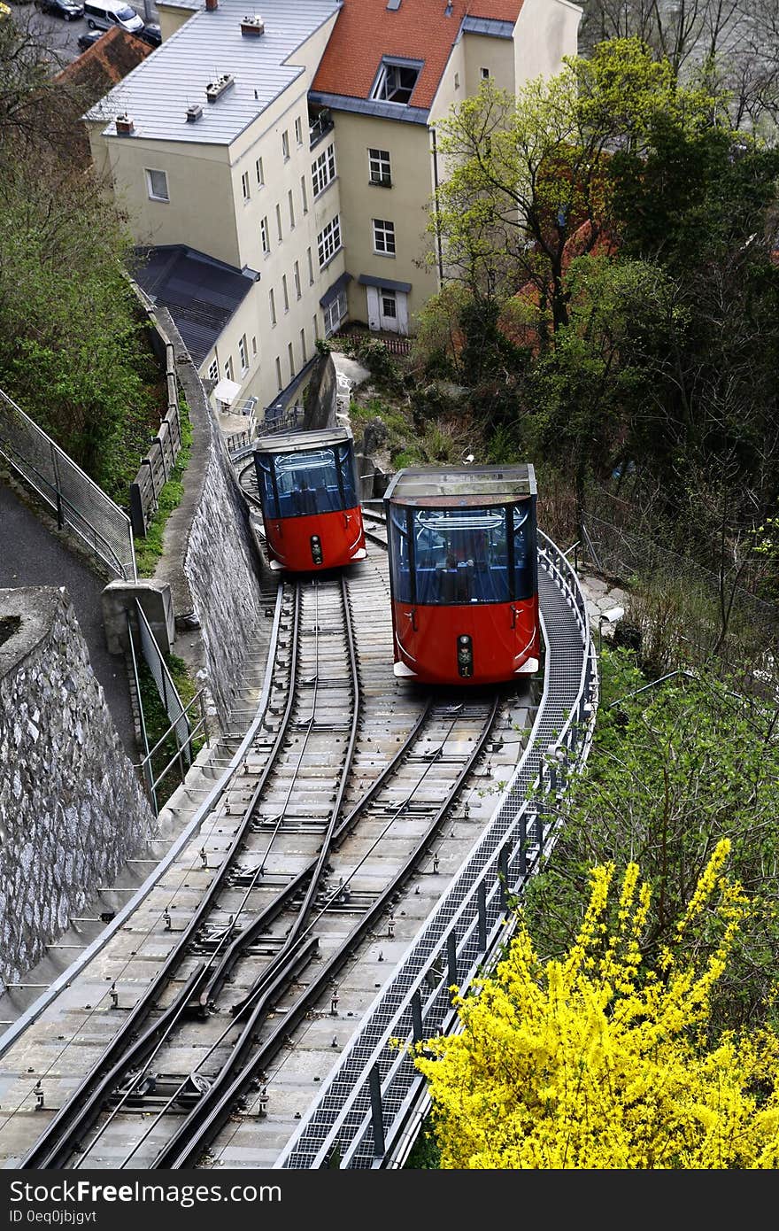 Red and Black Cable Train Uphill Near the Houses during Daytime