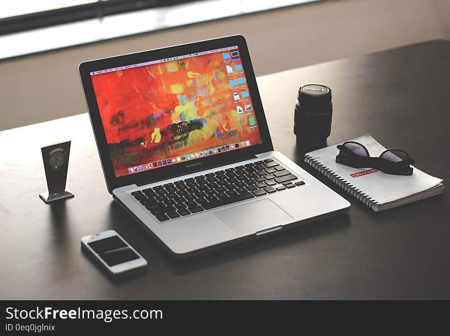 Apple computer on desktop with cellphone and accessories.