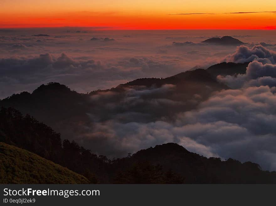 High View Photography of Mountain Ranges Surrounded With Clouds at Golden Hour