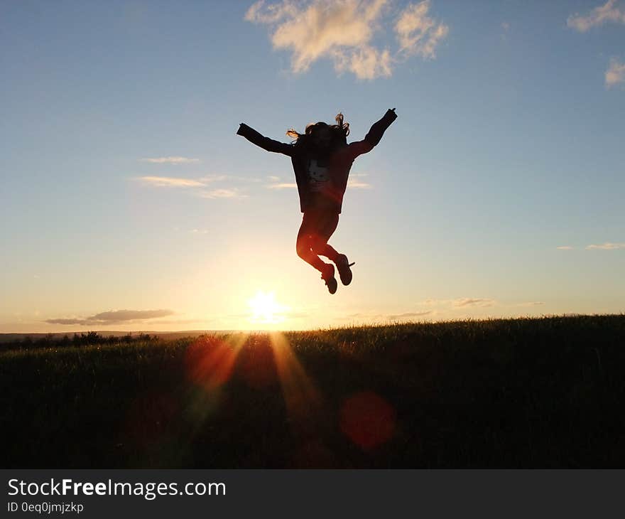 Silhouette Photo of a Person Jumping Nearby Green Grass Field during Golden Hour