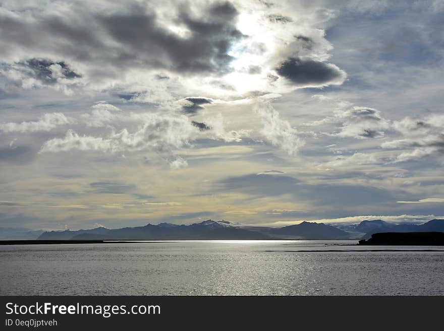 Brown Mountain Beside a Sea Under Grey Cloudy Sky