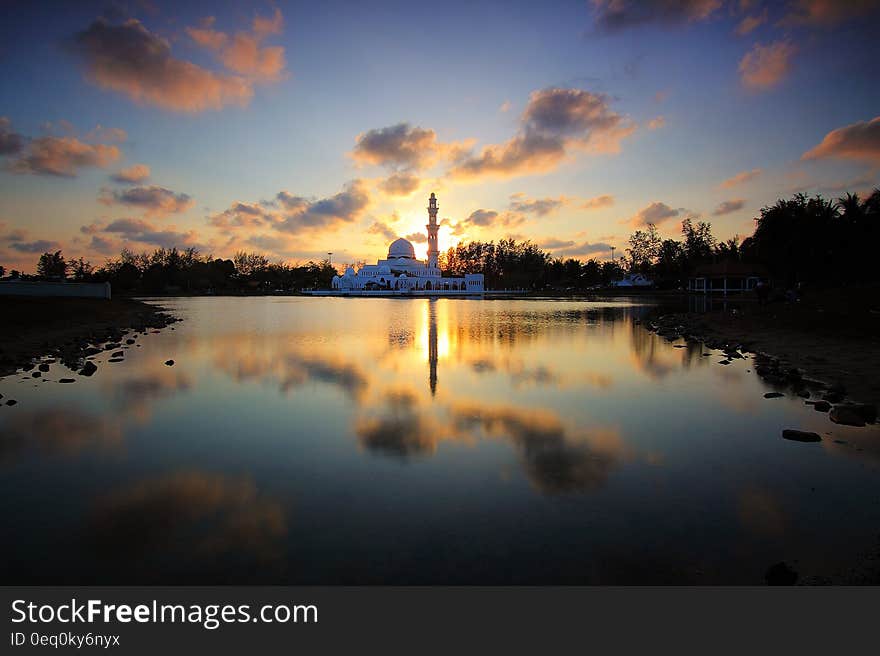 White Building Surrounded by Water and Trees during Golden Hour