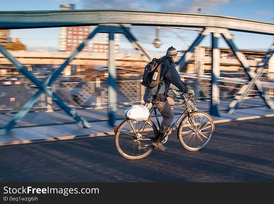 Man in Black Jacket Riding Black Bicycle in Gray Concrete Road in Panning Photography