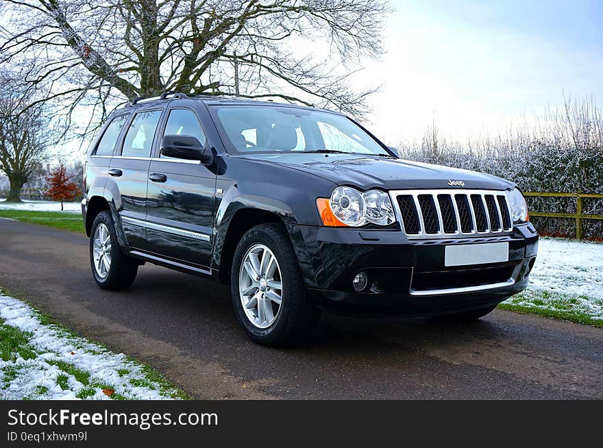 Black Jeep Suv on Black Asphalt Road Near on Snowy Grass Lawn