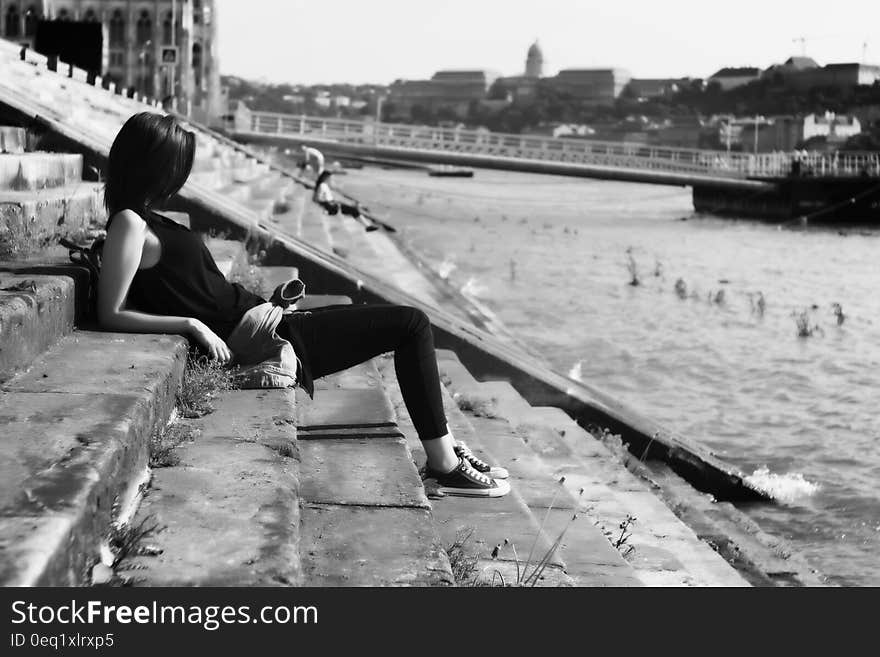 Woman on Black Shirt Sitting on Stairs in Front of River