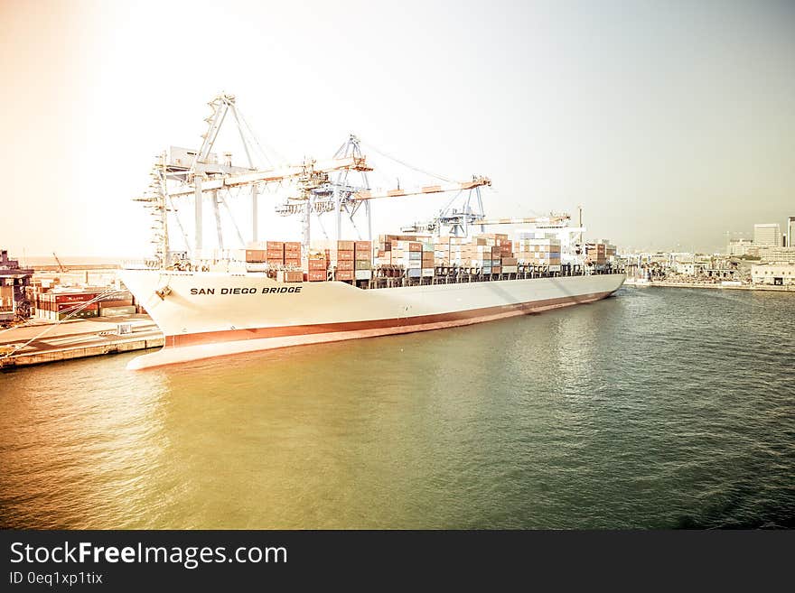 White and Orange Cargo Ship Docking during Daytime