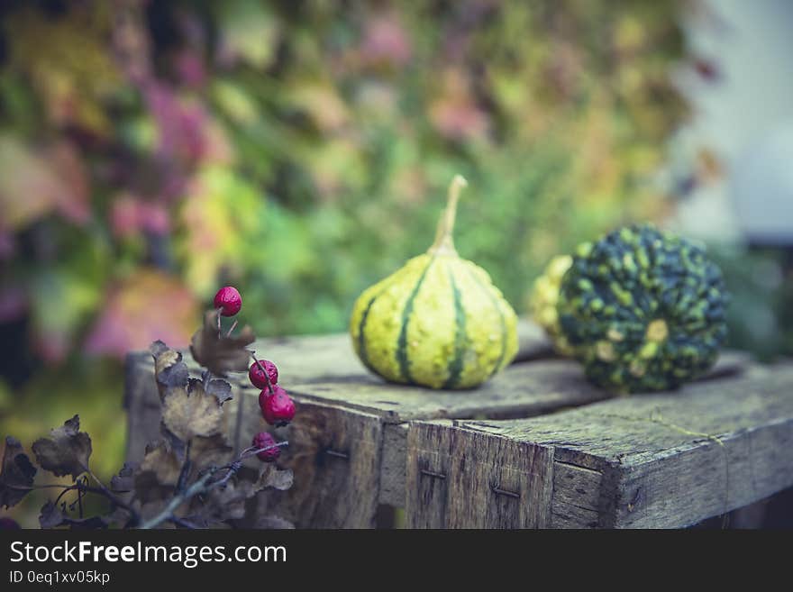 2 Green Fruit on Wooden Table Near Pink Small Fruit during Daytime