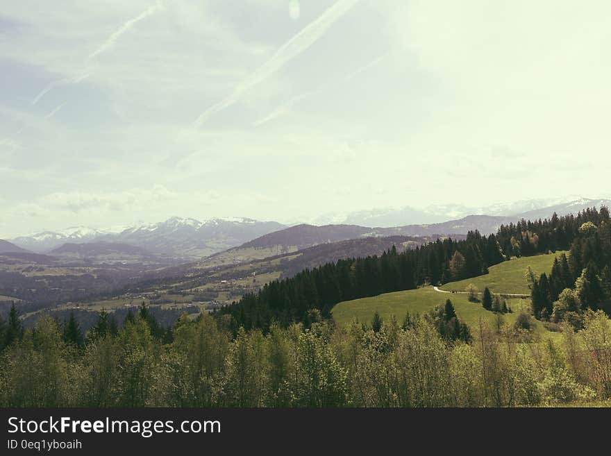 Green Grass Behind Brown Mountain Under White Sky