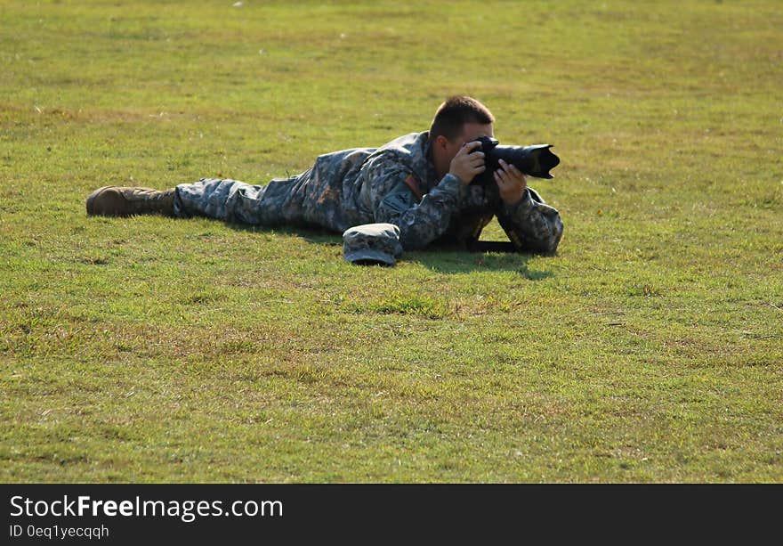 Military Crouching on Green Grass Using Dslr Camera during Daytime