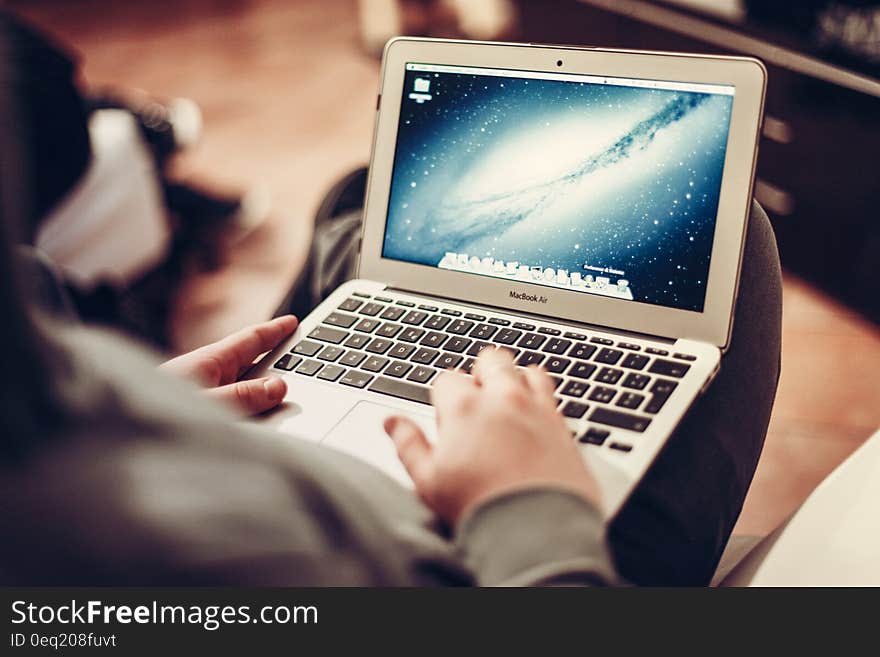 A person sitting and using a laptop computer. A person sitting and using a laptop computer.