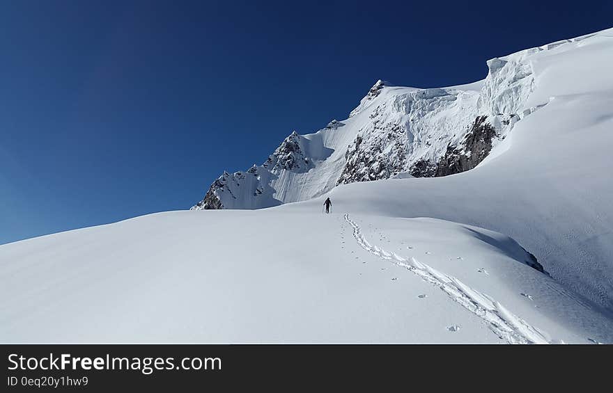 Man Walking in White Mountain Snow during Daytime