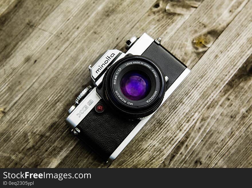 Black and Gray Minolta Dslr Camera on Top of Brown Wooden Surface