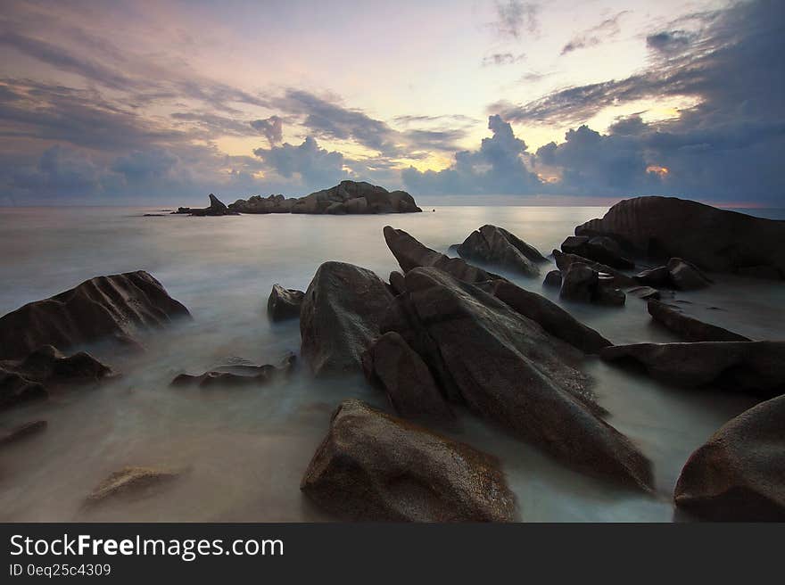 Blurs of water over rocks on sandy beach at sunset. Blurs of water over rocks on sandy beach at sunset.