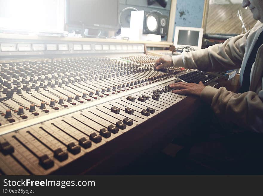 Hands moving knobs on sound mixing board inside modern recording studio. Hands moving knobs on sound mixing board inside modern recording studio.