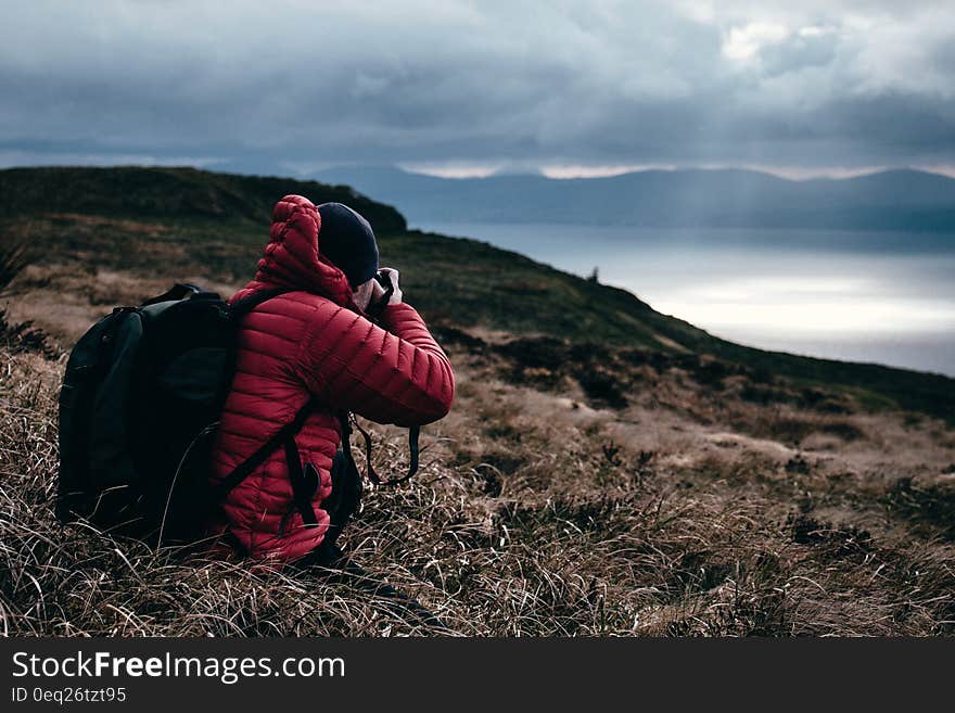 Person in Red Hoodie Taking a Photo of Wilderness