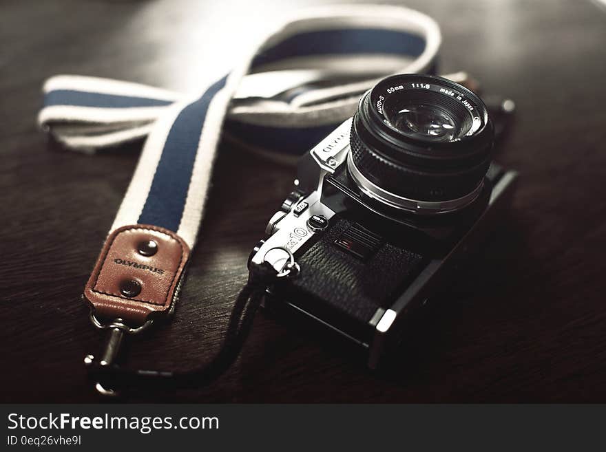 Vintage Olympus camera with cloth strap on desktop.