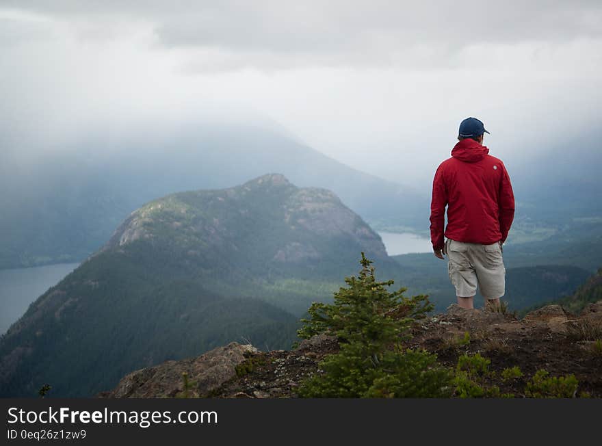 Hiker on hilltop overlooking alpine lake.