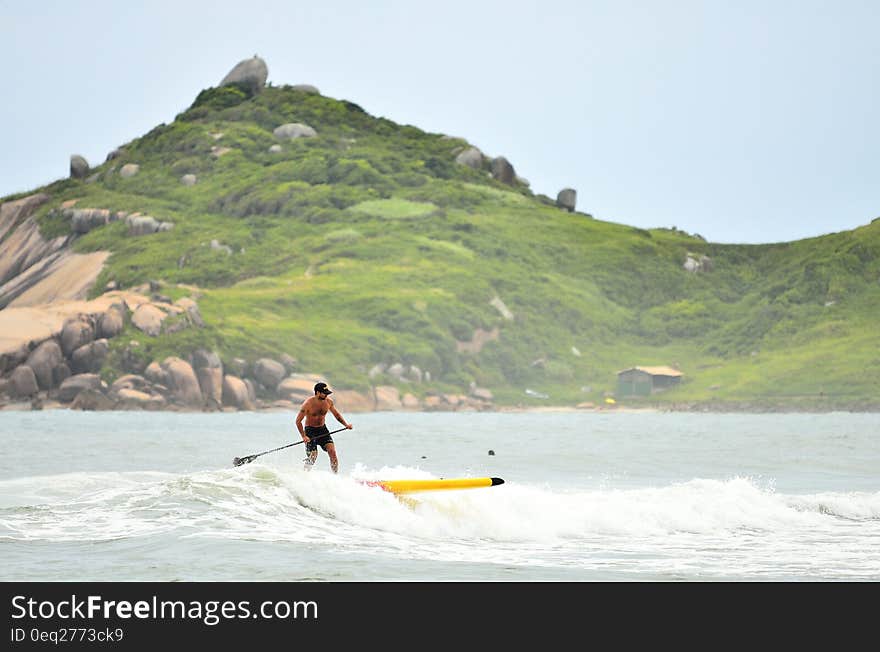 Man in Black Shorts Surfing Under Blue Sky during Daytime