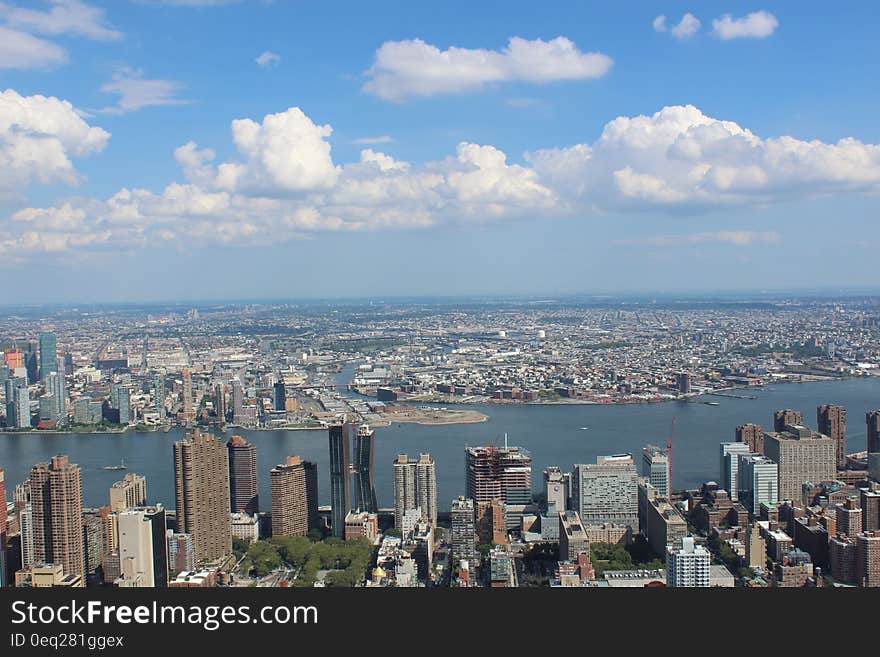 Aerial View of City Buildings by River Under Blue Cloudy Skies