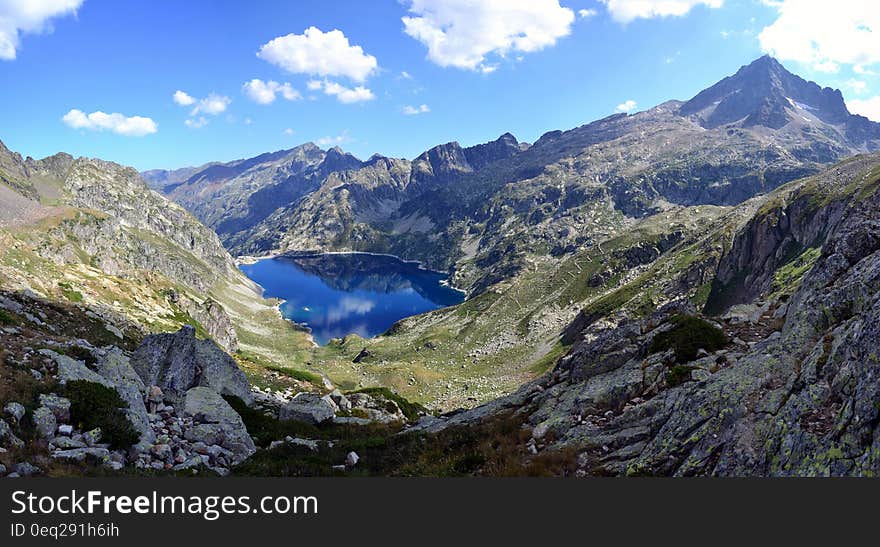 Lake Surrounded by Mountain Top Under Blue Sky at Daytime