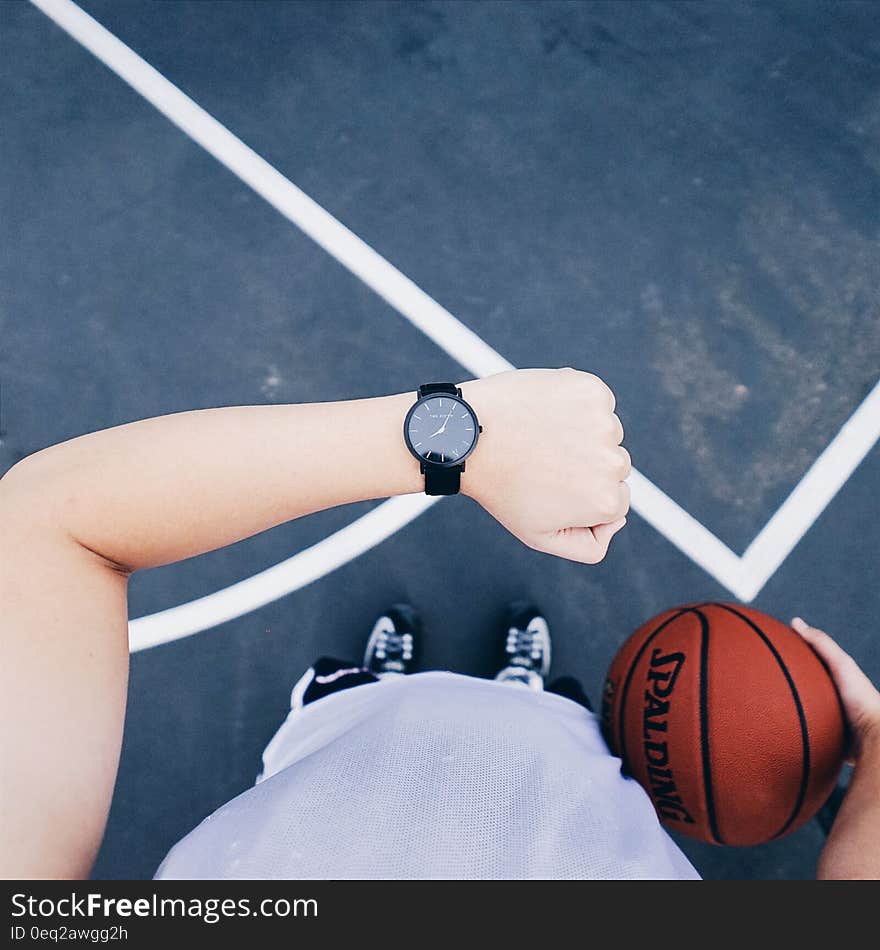 Person Wearing Black Round Analog Watch on Left Wrist While Holding Basketball on Right Hand