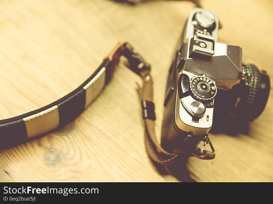 Black Camera With White and Black Strap on Beige Surface