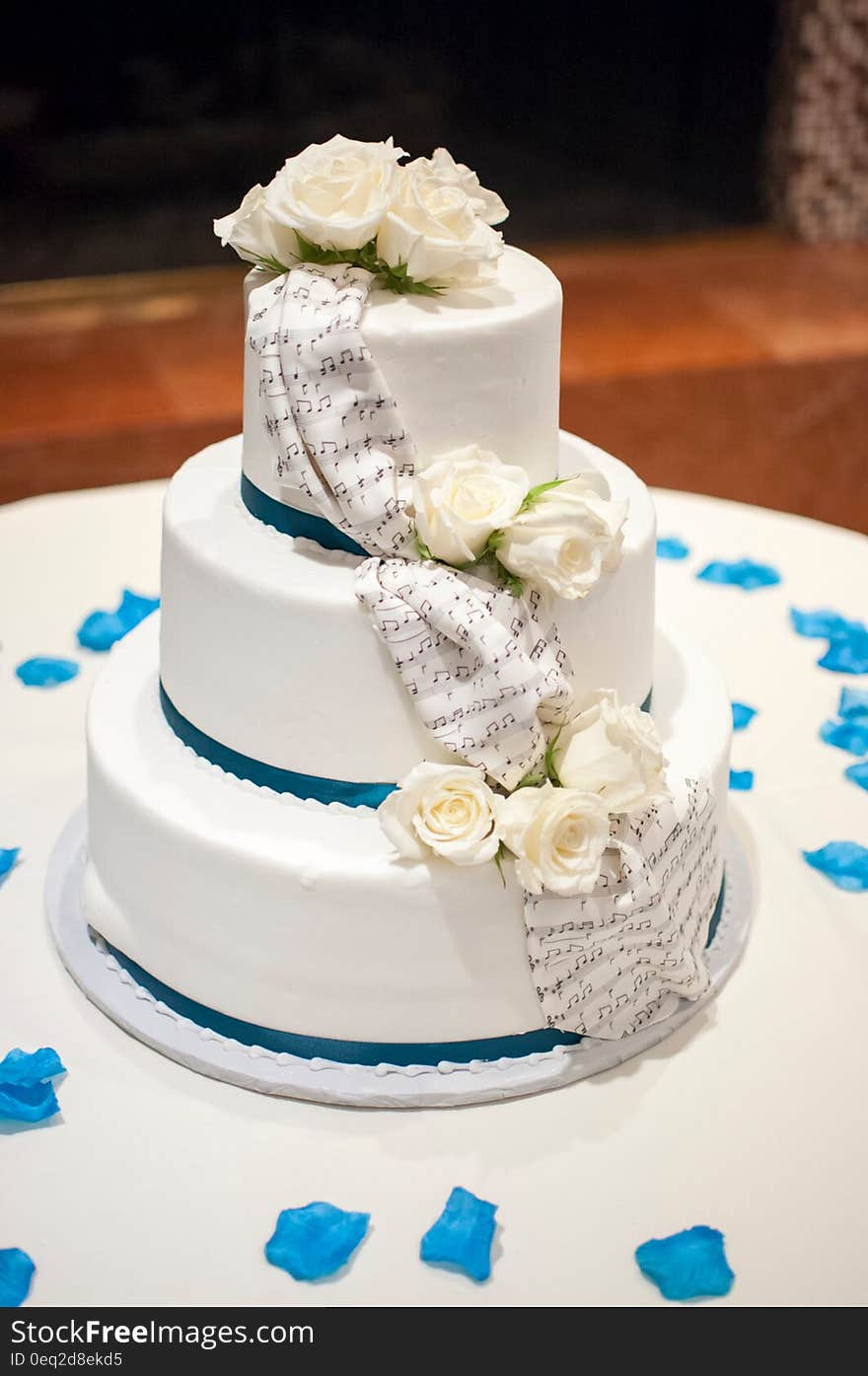 A close up of a wedding cake with decorative white roses.