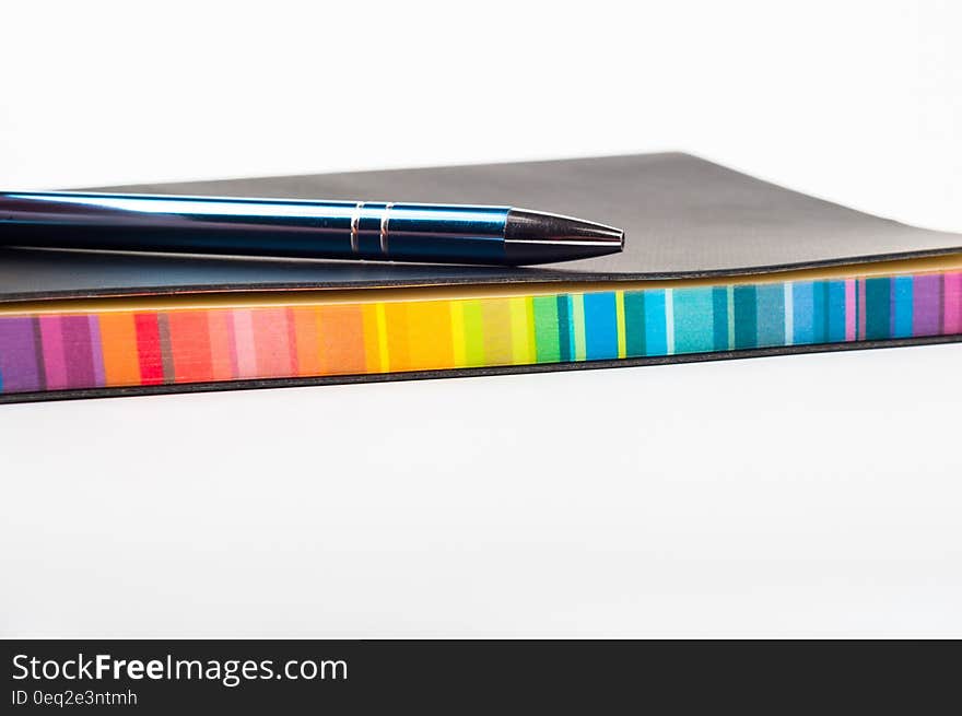 A colorful notebook with a pen on top.