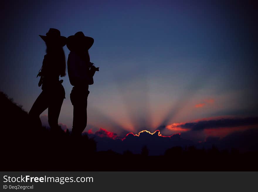 Silhouettes of people standing on a hill at sunset. Silhouettes of people standing on a hill at sunset.