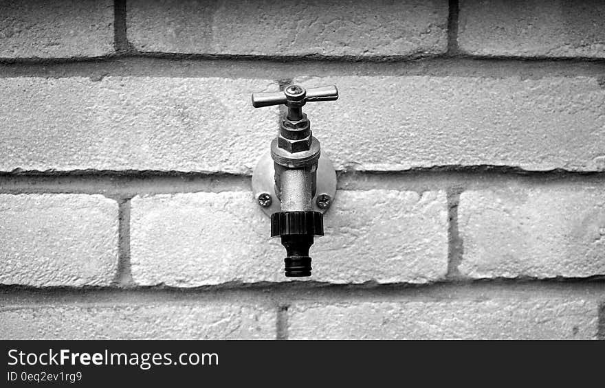 Grayscale of Metal Faucet on Wall Brick