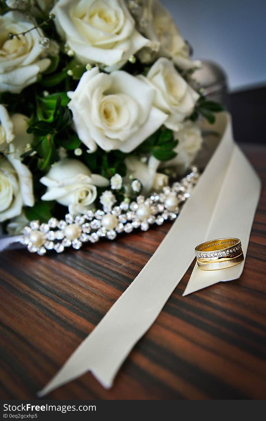 A wedding bouquet of white roses and gold rings. A wedding bouquet of white roses and gold rings.