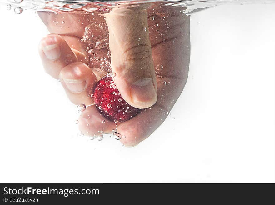 Person Holding Red Ball Underwater