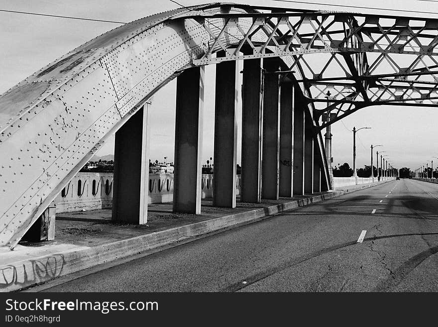 A black and white photo of a bridge with an arched metal structure. A black and white photo of a bridge with an arched metal structure.