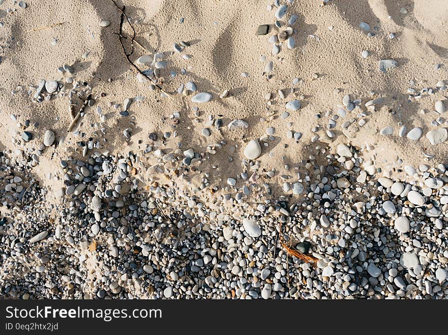 A close up of a beach with sand and pebbles. A close up of a beach with sand and pebbles.