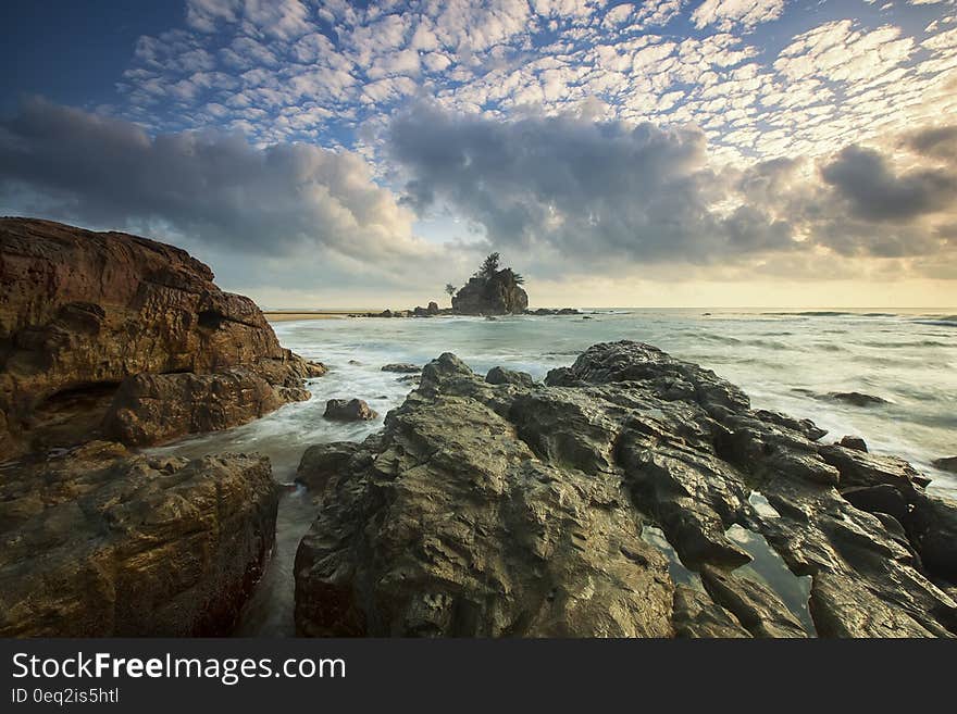 Brown Rocks on Seashore Under White Cloud Sky