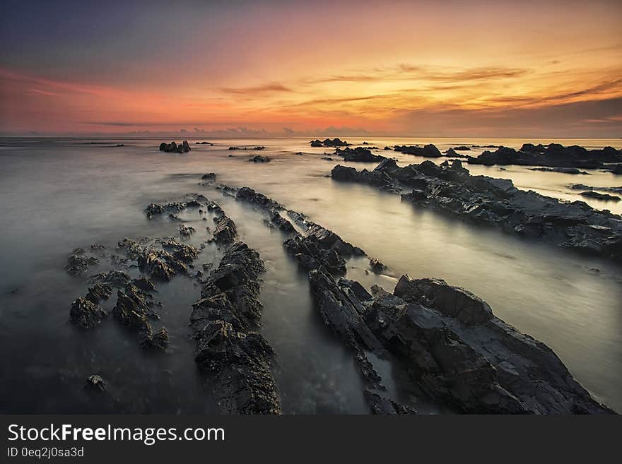 A rocky beach and colorful sky at sunset. A rocky beach and colorful sky at sunset.