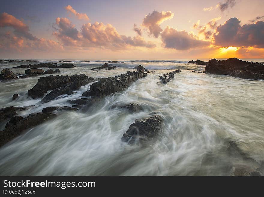 Pink Cloudy Sunset over Rocky Ocean