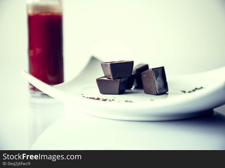 Chocolate cubes on a white plate and red juice in the background. Chocolate cubes on a white plate and red juice in the background.