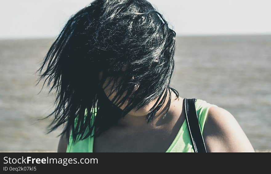 A portrait of a woman standing in the wind with hair over her face, open sea in the background. A portrait of a woman standing in the wind with hair over her face, open sea in the background.