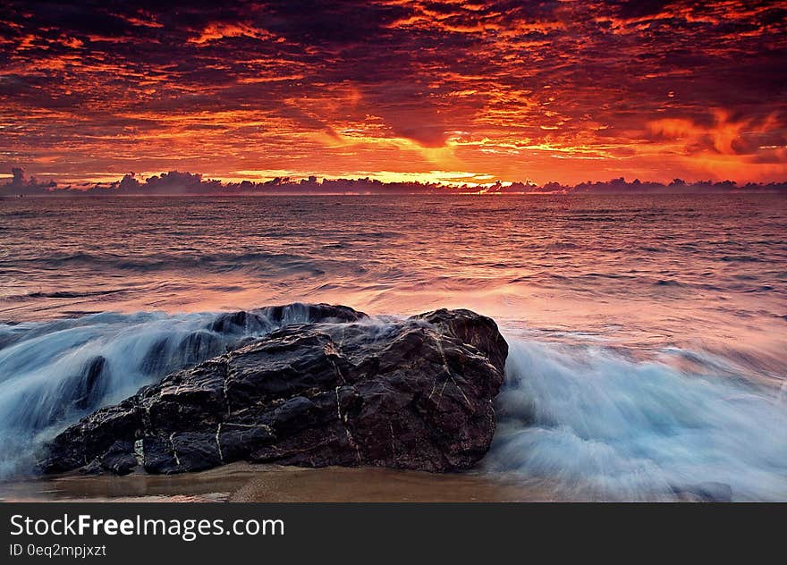 A sunset on the beach with waves hitting the rocks. A sunset on the beach with waves hitting the rocks.