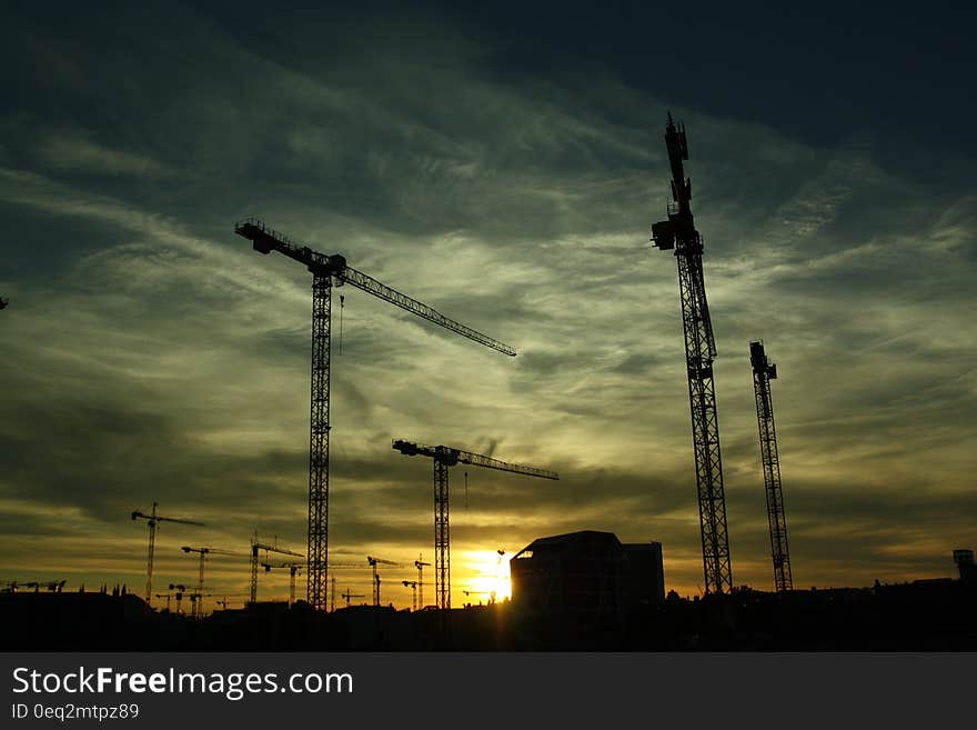 A construction site at sunset with tower cranes.