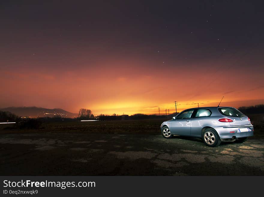 A car parked on field at sunset. A car parked on field at sunset.