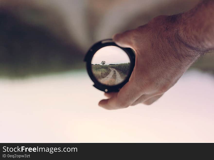 A man holding a lens showing the world in focus with defocused background. A man holding a lens showing the world in focus with defocused background.