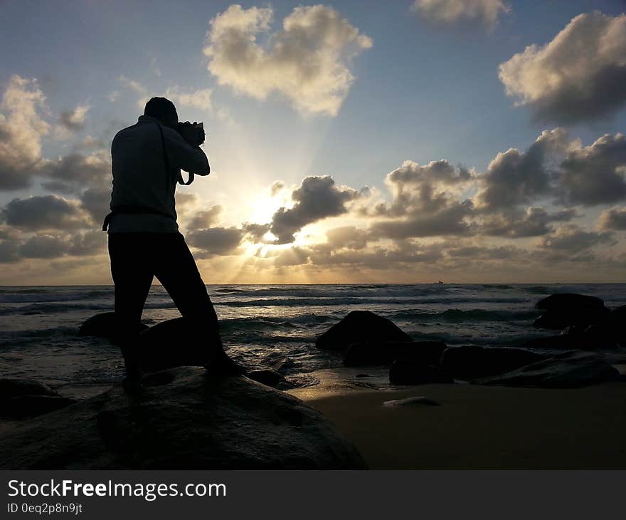 Person Capturing Photo Near Sea Under Clear Blue and White Cloudy Sky during Daytime