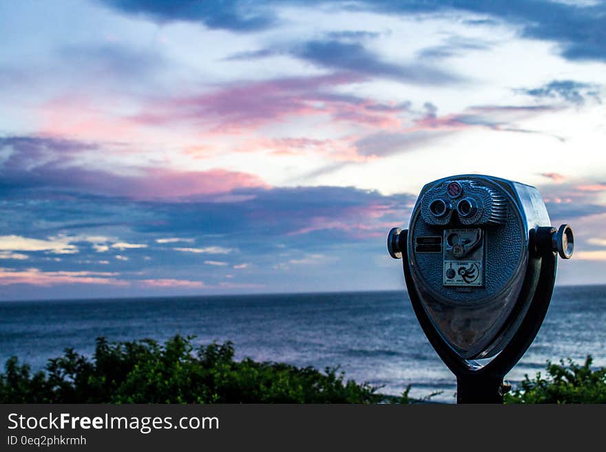 Gray and Black Tower Viewer Near Green Grass Field and Beach Under Blue White and Gray Clouds