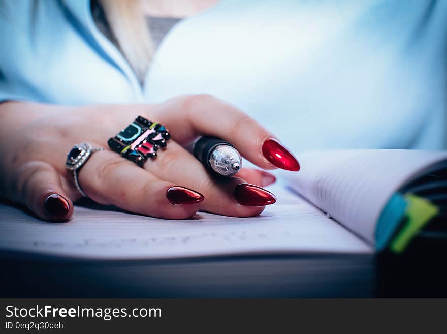 Person With Red Nail Polish Holding Black Pen