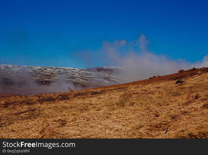 Dry grass covered hillside with smoke rising in background. Dry grass covered hillside with smoke rising in background.