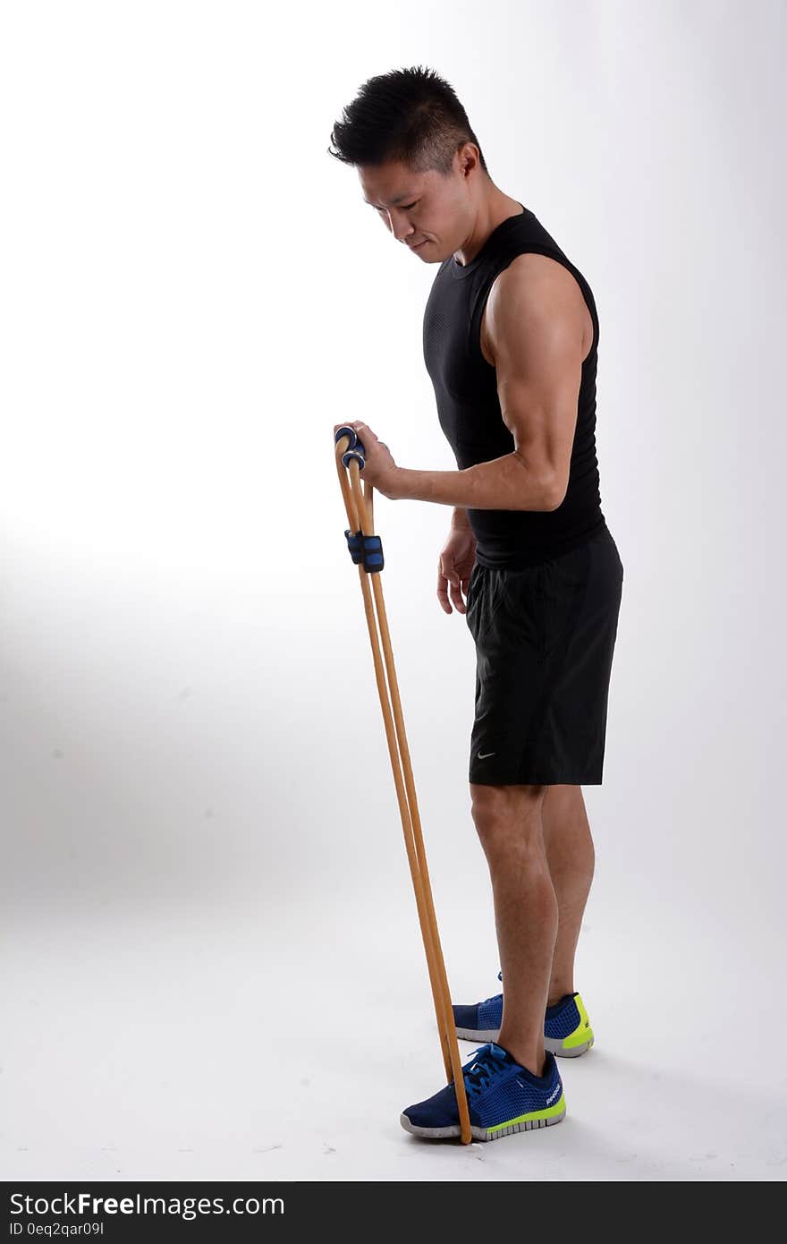 Man in Black Tank Top Holding Brown Stretching Rope