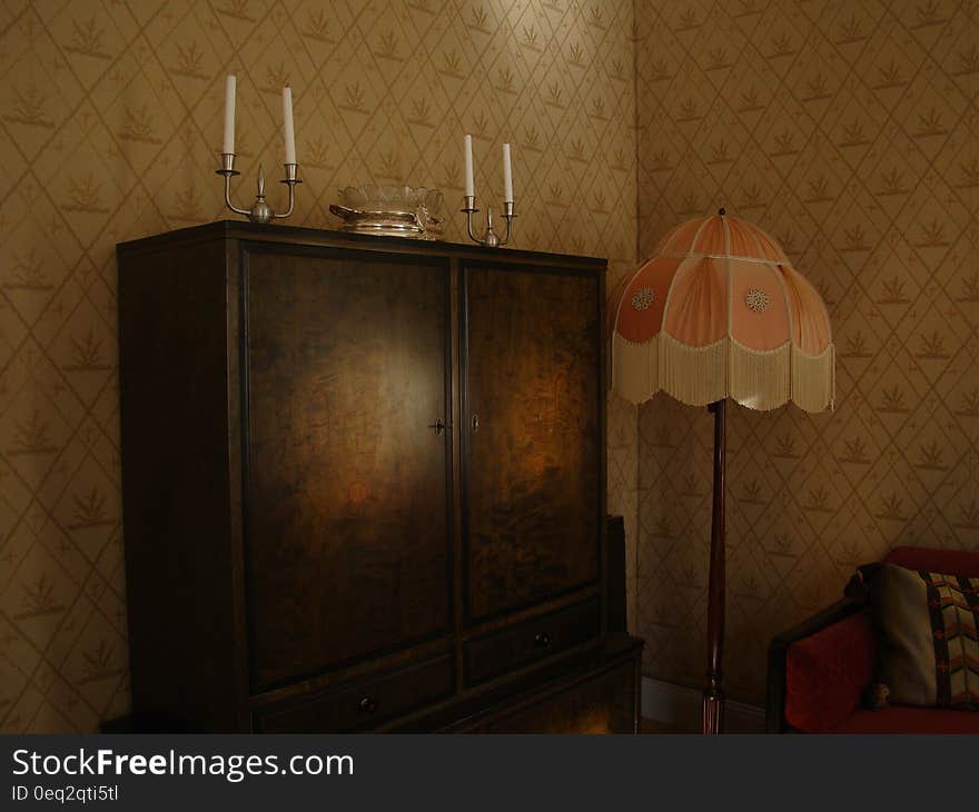 Black Wooden Wardrobe and White and Pink Pedestal Lamp Inside the Room